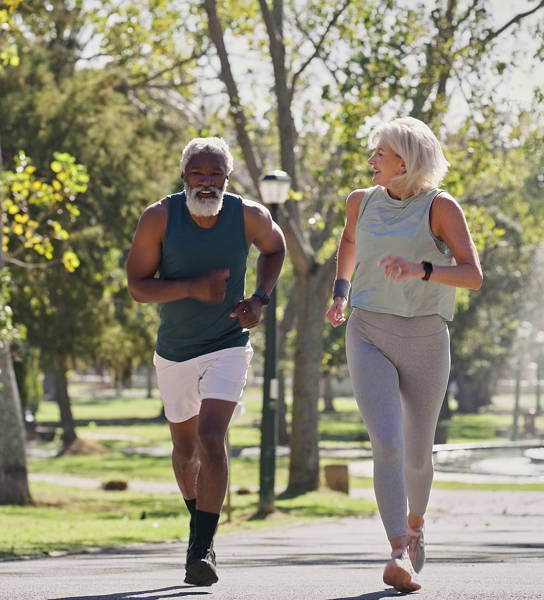 Fitness, senior people or running in park for wellness, cardio exercise or training in retirement. Elderly couple, smile or outdoor for workout with support, motivation or friends on path with energy
