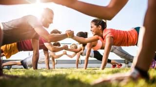 Low angle view of athletes cooperating while exercising on a sports training outdoors. Focus is happy couple.