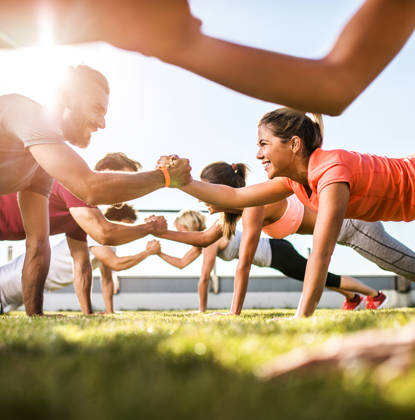 Low angle view of athletes cooperating while exercising on a sports training outdoors. Focus is happy couple.
