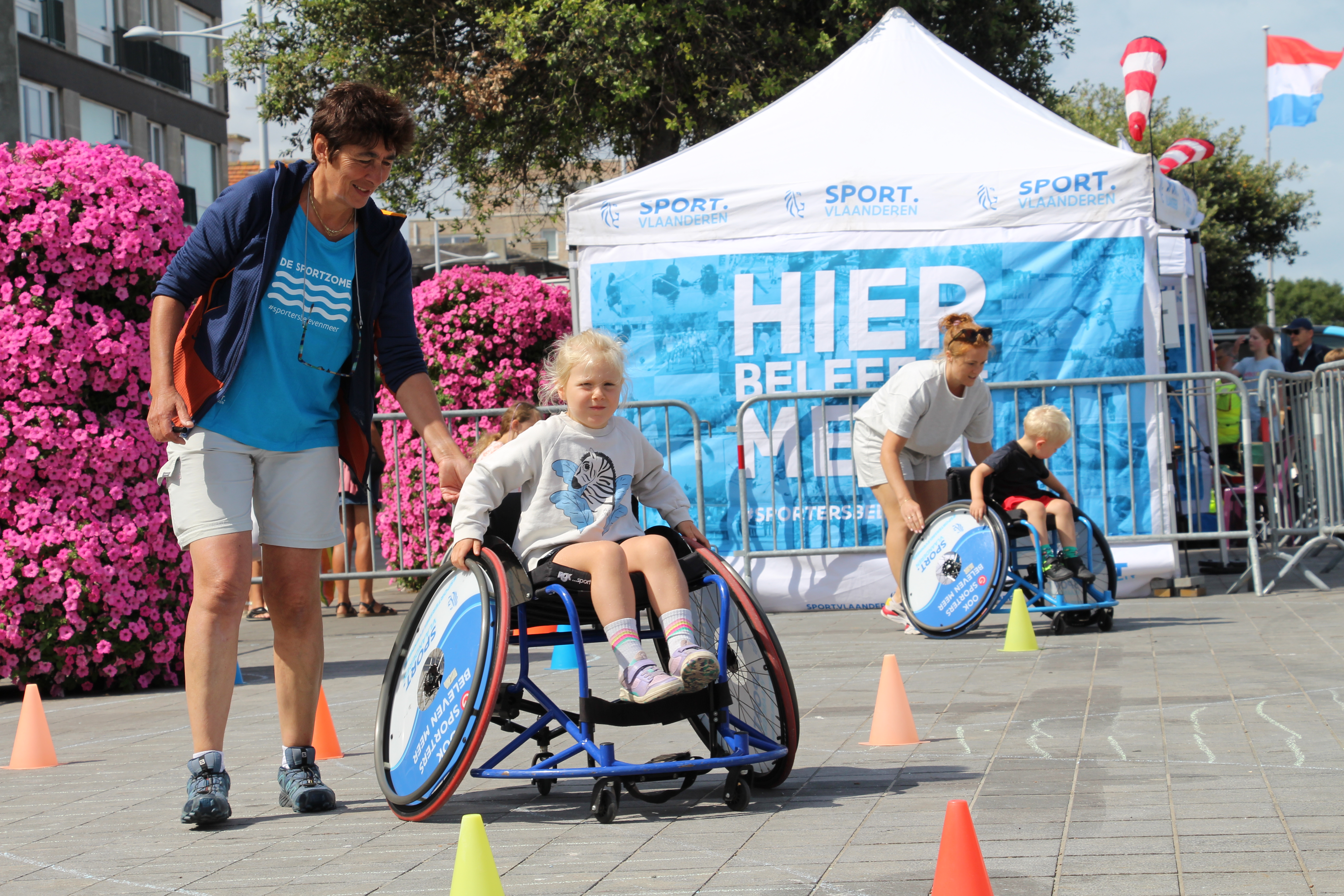 Meisje en jongetje in een rolstoel volgen een parcours onder begeleiding