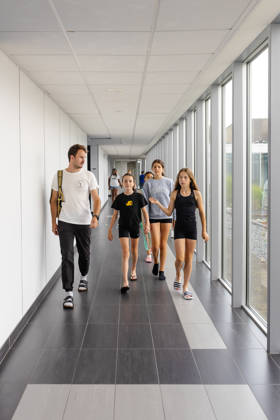 kinderen met leerkracht stappen in de gang van het sportverblijf