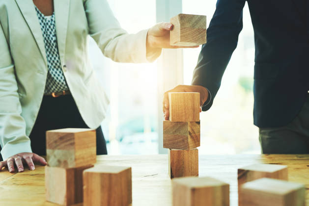 Shot of two unrecognisable businesspeople stacking wooden blocks together in an office