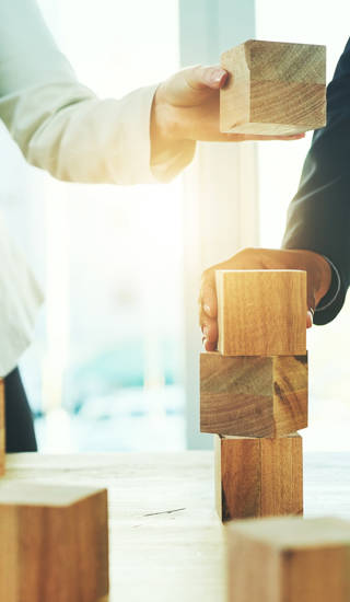 Shot of two unrecognisable businesspeople stacking wooden blocks together in an office