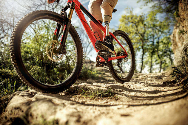 man with a prosthetic leg ride a mountain bike on a hill