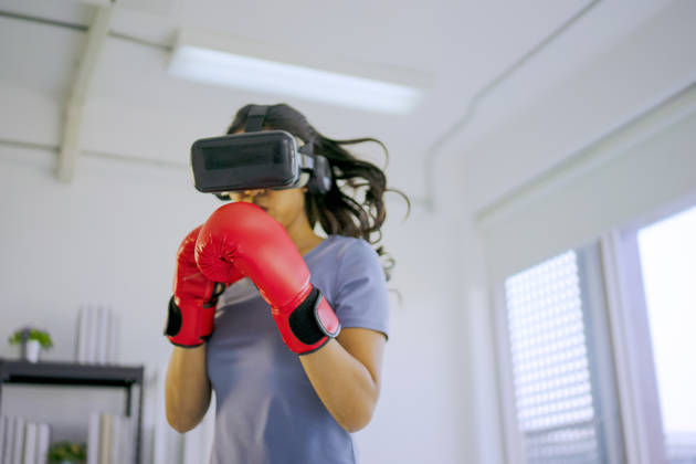 Young woman is exercise with virtual reality glasses.  She is boxer. Active solo daily life and technology concept.