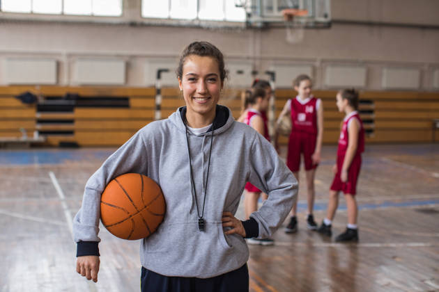 Vrouwelijke basketbalcoach met een jong team in sporthal