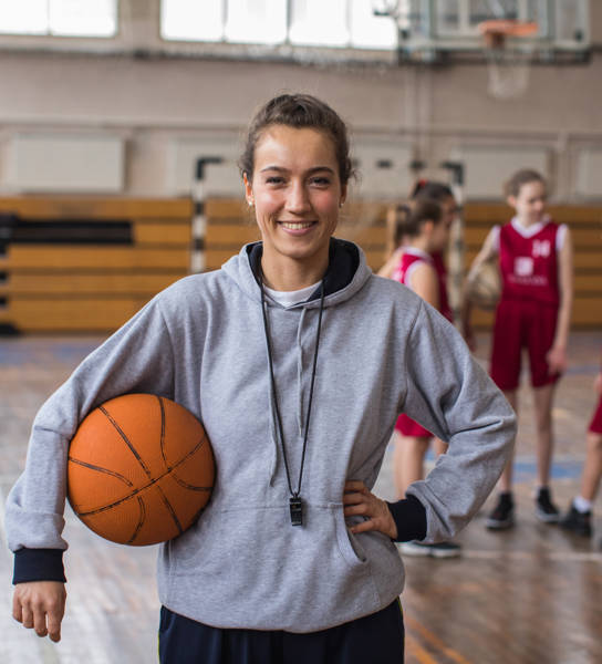 Vrouwelijke basketbalcoach met een jong team in sporthal