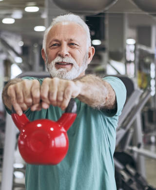Oude man met gewichtsbal voor hem uitgestrekt
