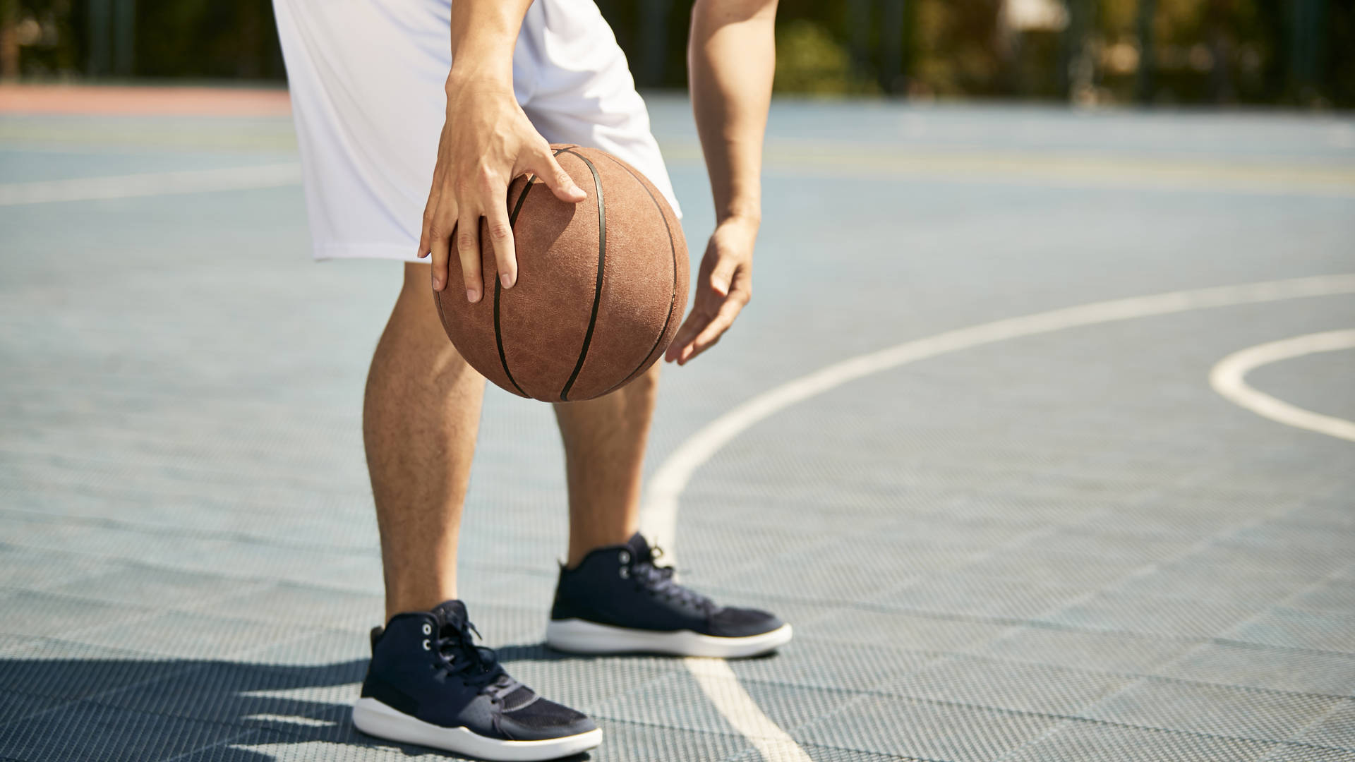 jonge basketter dribbelt met bal, enkel benen zichtbaar