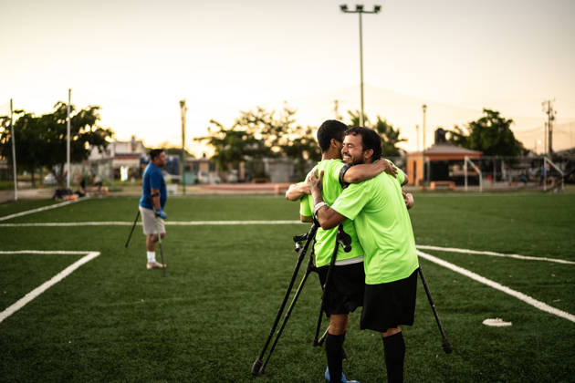 Amputee soccer players celebrating after scoring a goal on the soccer field