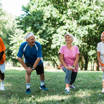 cheerful senior and multicultural people doing stretching exercise on grass