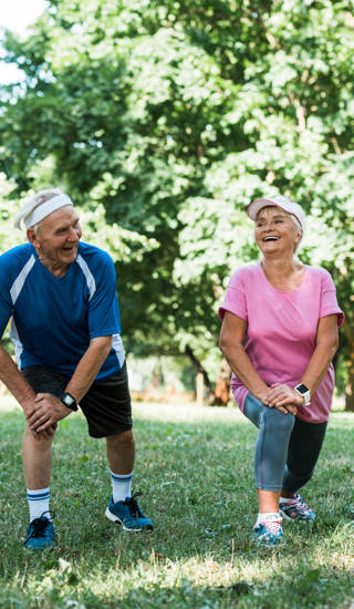 cheerful senior and multicultural people doing stretching exercise on grass