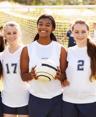 Members Of Female High School Soccer Team Smiling To Camera