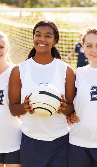 Members Of Female High School Soccer Team Smiling To Camera