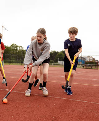 kinderen spelen hockey op buitenterrein
