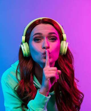Photo of charming positive woman wear green sweatshirt headphones enjoy songs asking keep silence isolated neon blue color background.