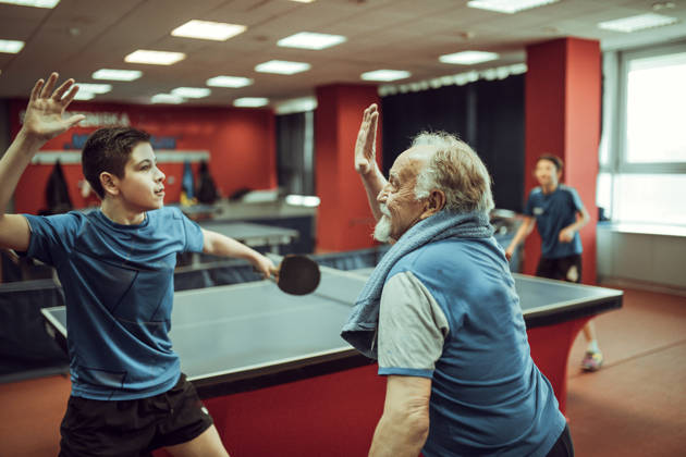 Opa en kleinzoon spelen tafeltennis en doen high five