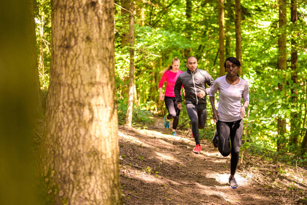 Front view of man and women running on footpath in forest.
