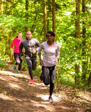 Front view of man and women running on footpath in forest.