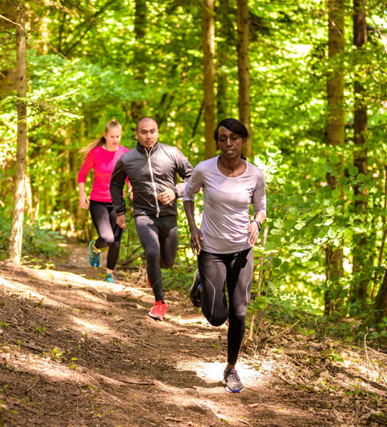 Front view of man and women running on footpath in forest.