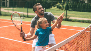 Meisje met coach op gravel tennisveld