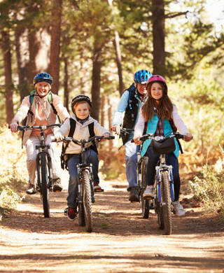 Grandparents and kids cycling on forest trail, California