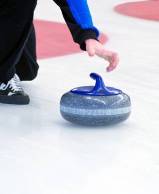 Curling speler schuift steen over ijs