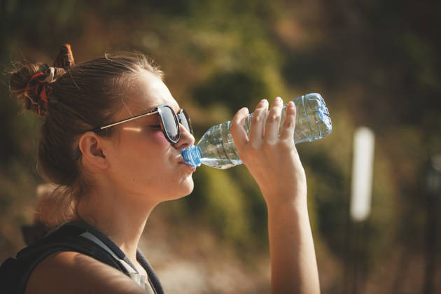Zij-aanzicht van vrouw die flesjes water drinkt