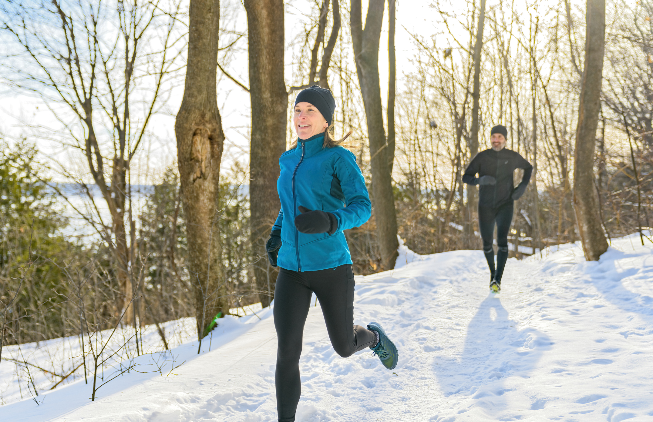A mature couple in the winter running together in nature
