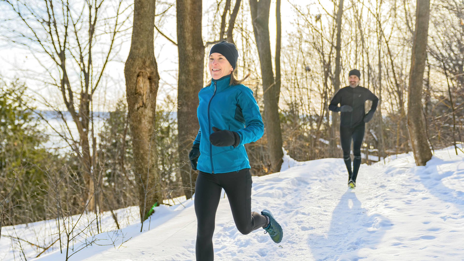A mature couple in the winter running together in nature