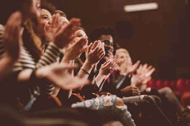 Group of people clapping hands in the theater, close up of hands. Dark tone.
