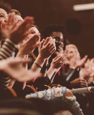 Group of people clapping hands in the theater, close up of hands. Dark tone.