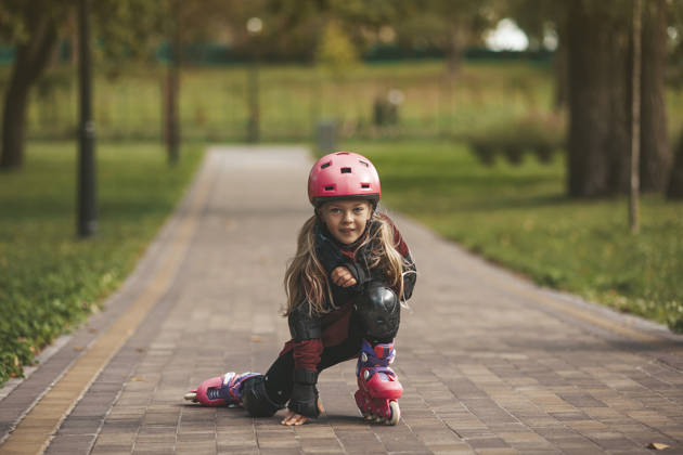 Meisje met helm op rolschaatst op de weg