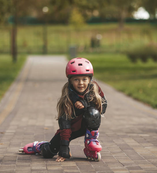 Meisje met helm op rolschaatst op de weg