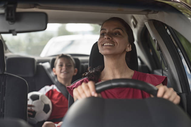 Happy soccer mom transporting kid to football practice in her car â lifestyle concepts