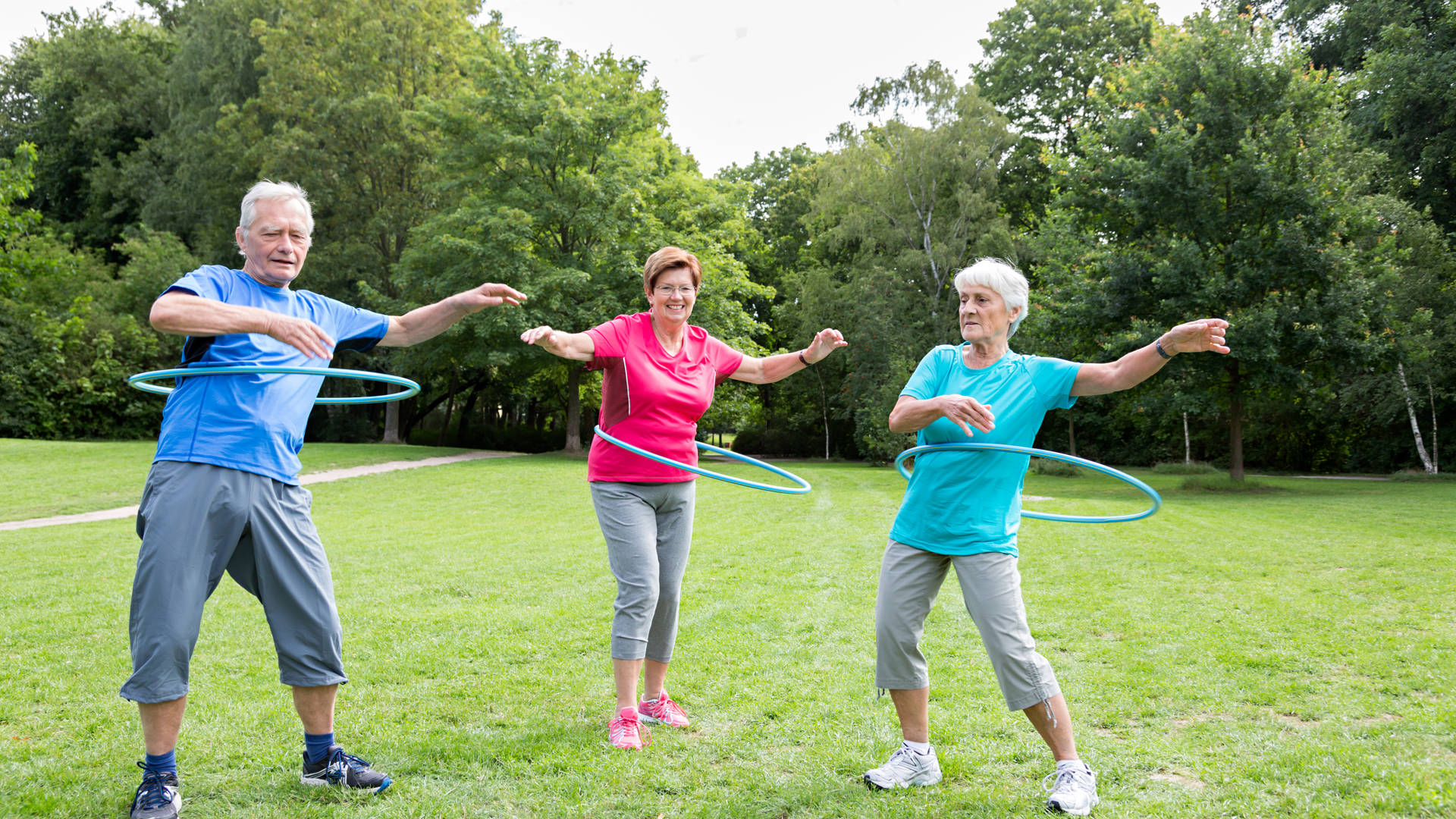 Drie senioren met hoelahoep in park