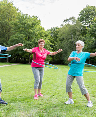 Drie senioren met hoelahoep in park