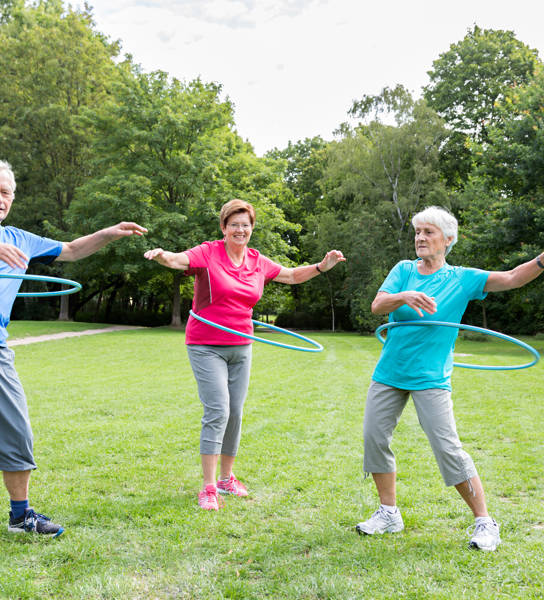 Drie senioren met hoelahoep in park