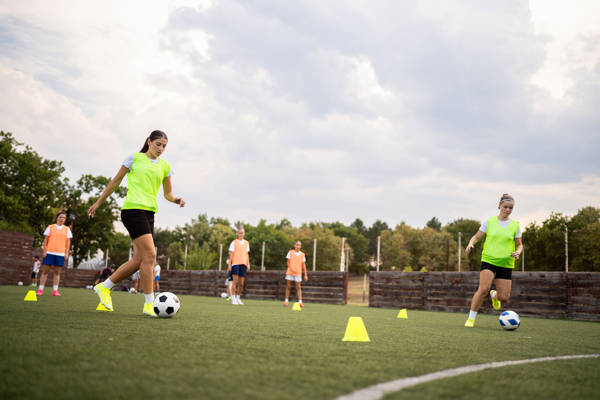Caucasian teenage girl, a soccer players dribbling the soccer ball between the sports cones, during an soccer practice