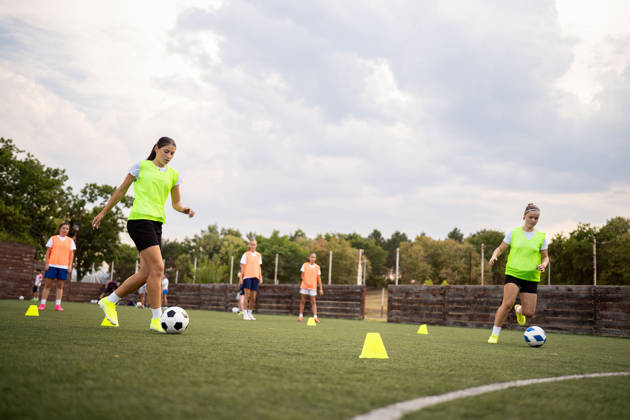 Caucasian teenage girl, a soccer players dribbling the soccer ball between the sports cones, during an soccer practice