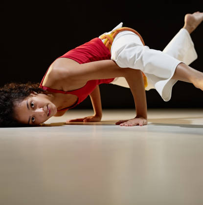 portrait of young adult latin american female doing yoga and capoeira in gym. Horizontal shape, full length, side view, copy space