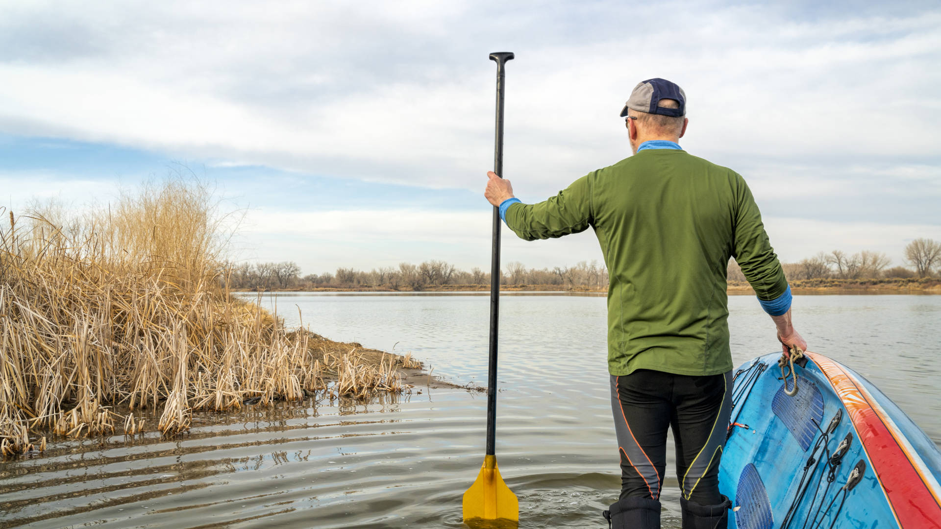 early spring stand up paddling, senior male with his paddleboard on lake in Colorado