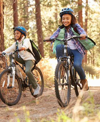 Grandparents With Children Cycling Through Fall Woodland