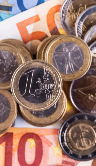 Euromunten 1 en 2 euro bovenop eurobiljetten van verschillende waardes