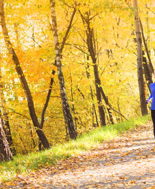 Active and sporty woman runner is exercising in colorful autumn nature