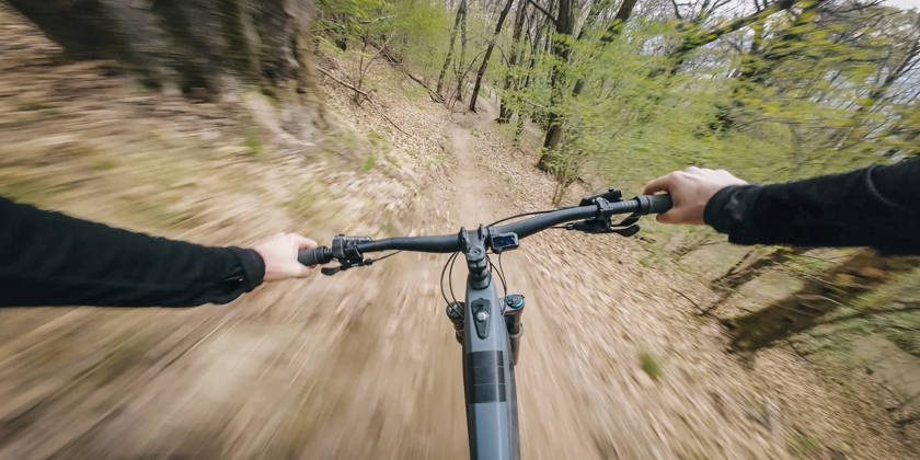 Motion blur as young man rides through springtime forest, in the Swiss Alps