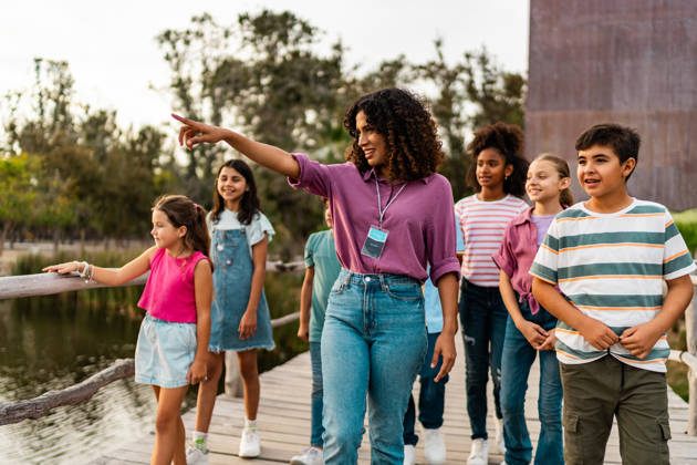 Young teacher walking and talking to students during field trip