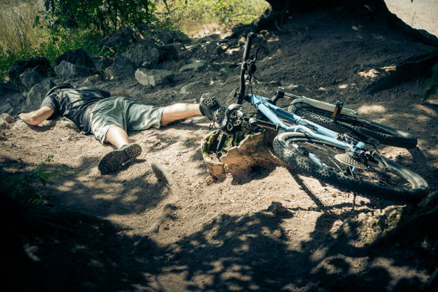 Young mountain biker fallen off his bike when going down a dangerous trail