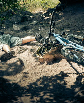 Young mountain biker fallen off his bike when going down a dangerous trail