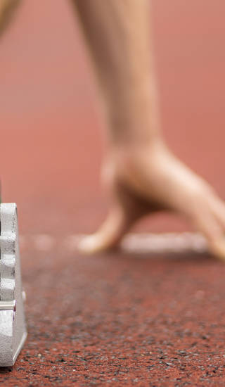 Close-up van hand en voet in startblok